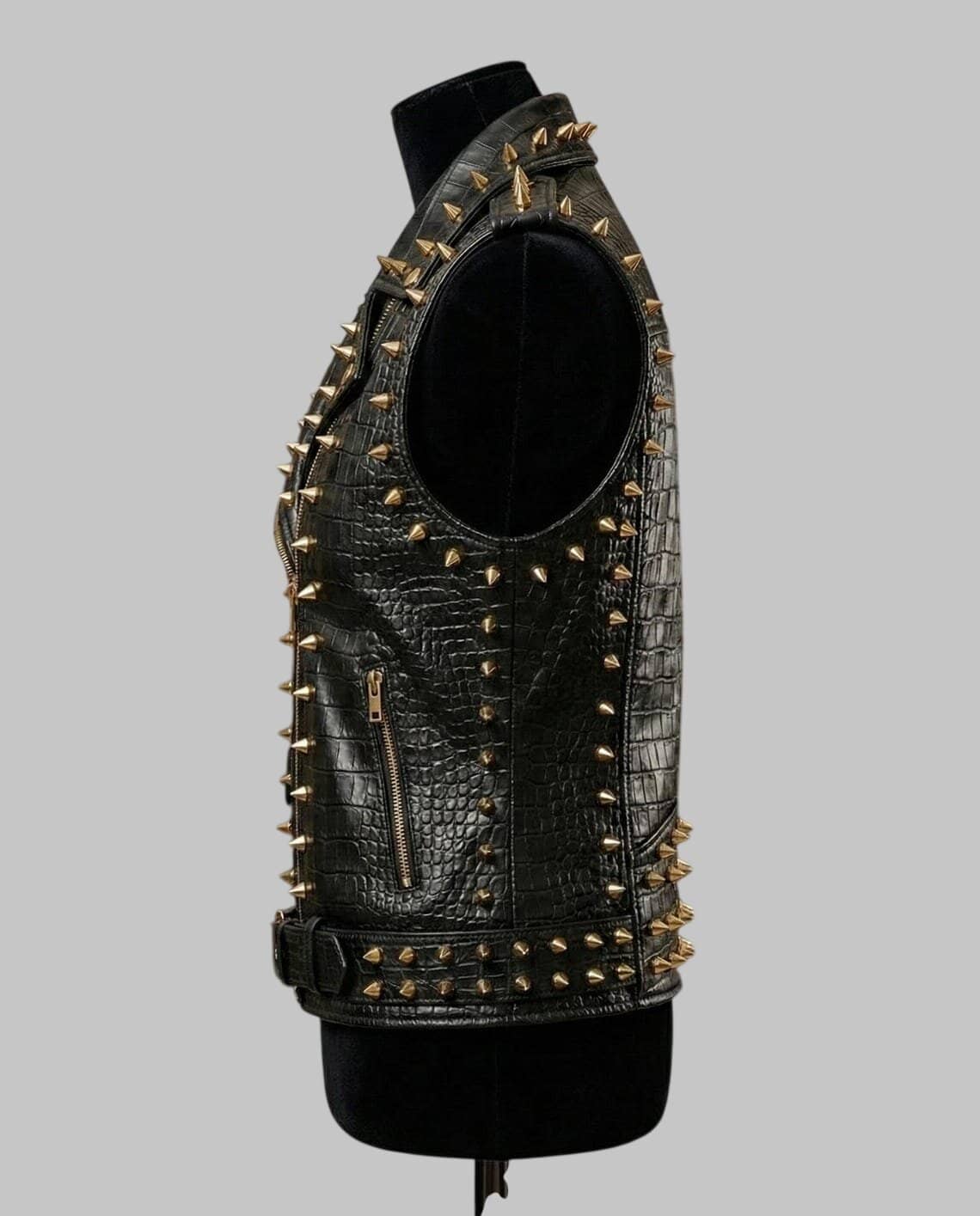 Black crocodile-embossed leather vest with gold-tone metal studs and zippers, displayed on a black mannequin torso against a solid gray background.